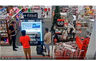 Three men standing in front of a fitbit display at kohl's