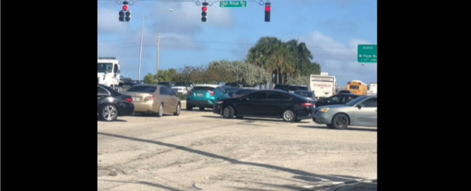 Cars stuck in traffic with a red traffic signal.