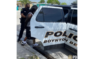 Police officer putting a man into the backseat of a police car.