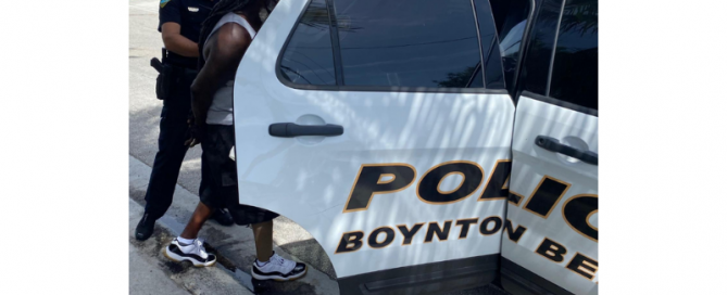 Police officer putting a man into the backseat of a police car.