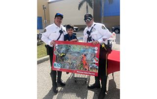 Two police officers standing next to a young boy who is holding toys; they are all in front of Walmart.