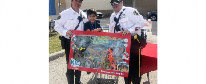 Two police officers standing next to a young boy who is holding toys; they are all in front of Walmart.