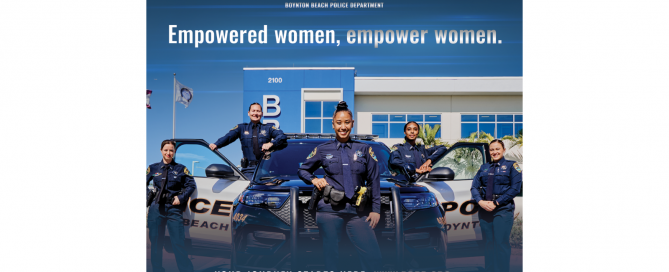 5 female police officers standing next to police car in front of police department
