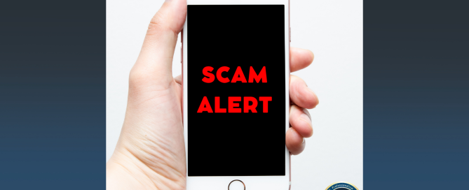 Hand holding a cell phone that shows scam alert on the screen